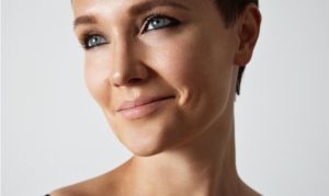 Close-up of a smiling woman with blue eyes and short hair.